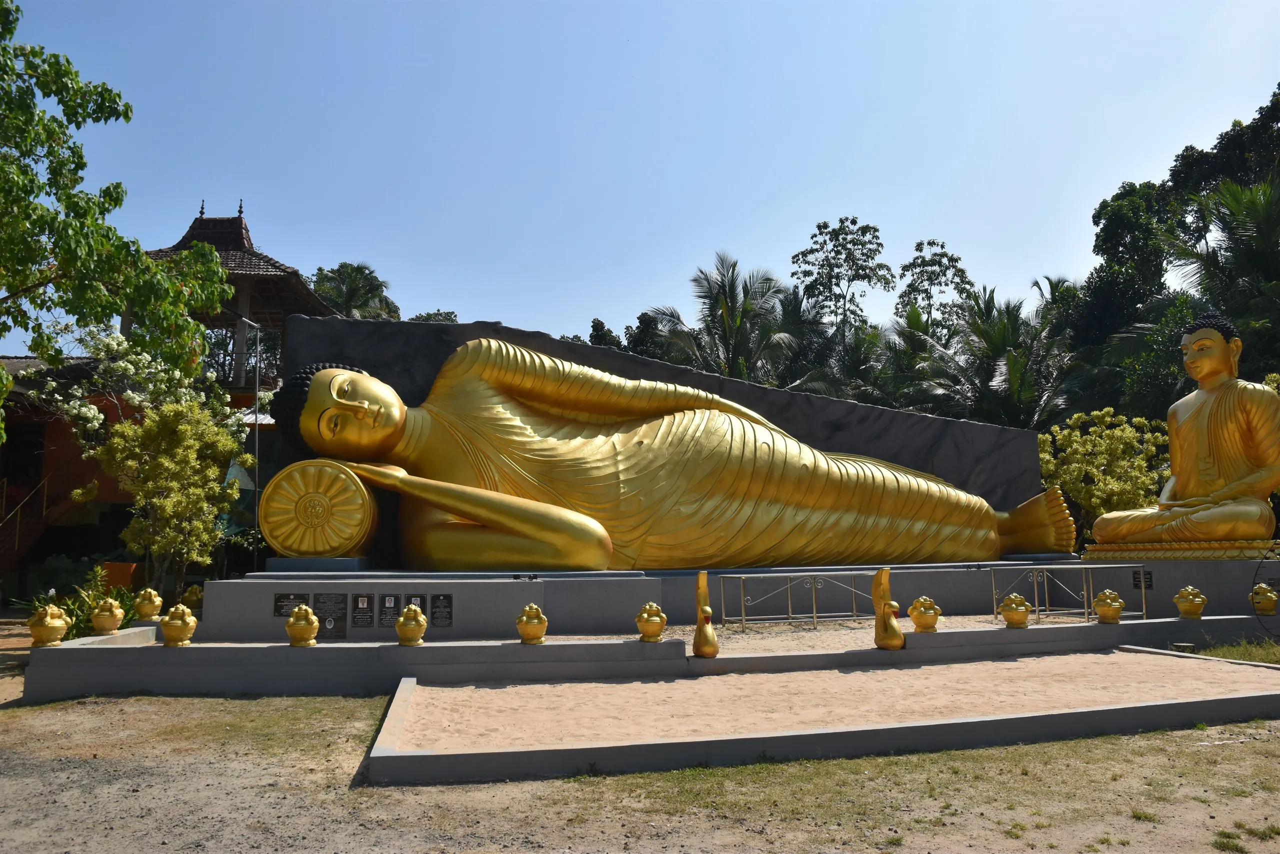 A large golden reclining Buddha in a temple garden