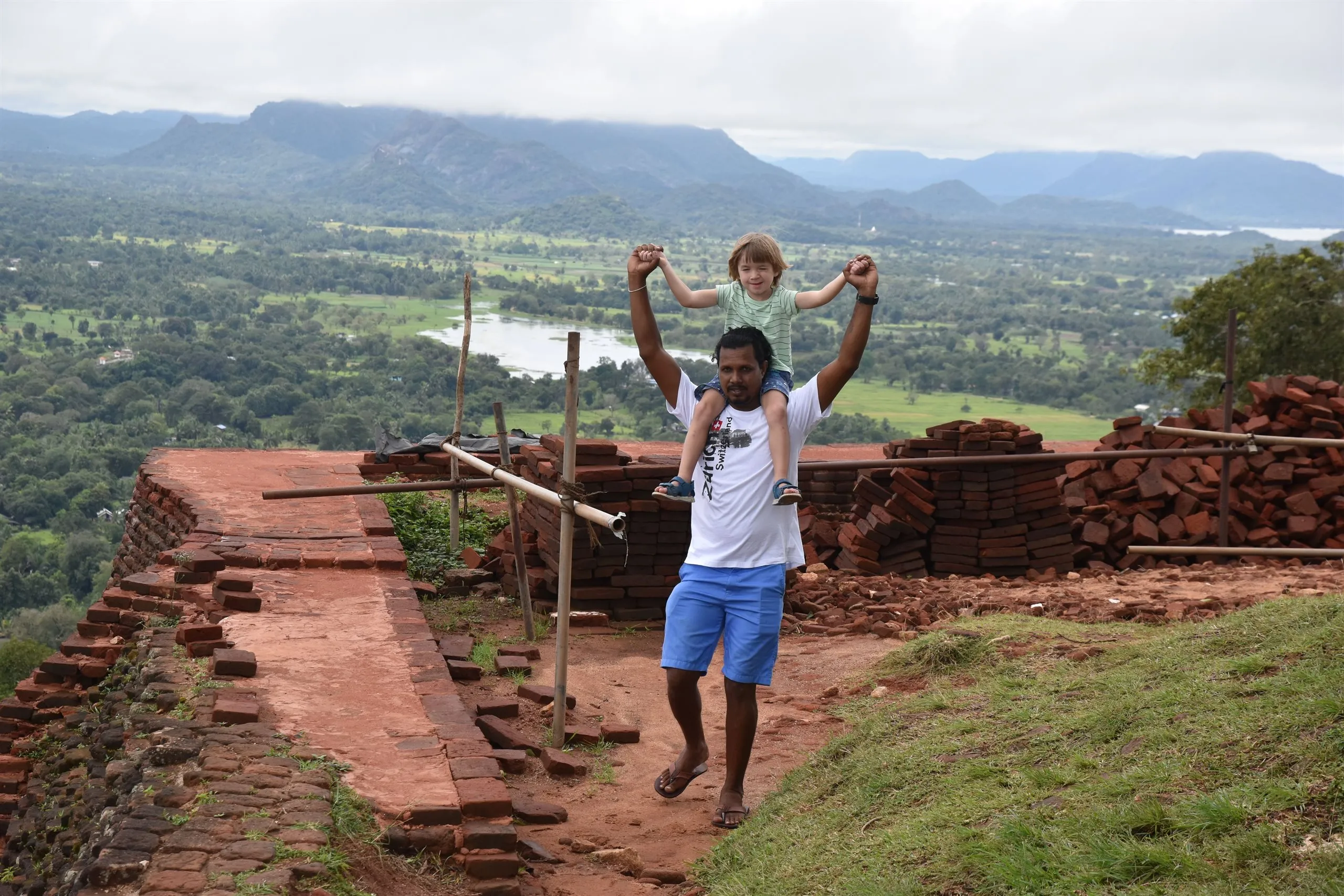 A guide lifting a young guest into the air above the hills