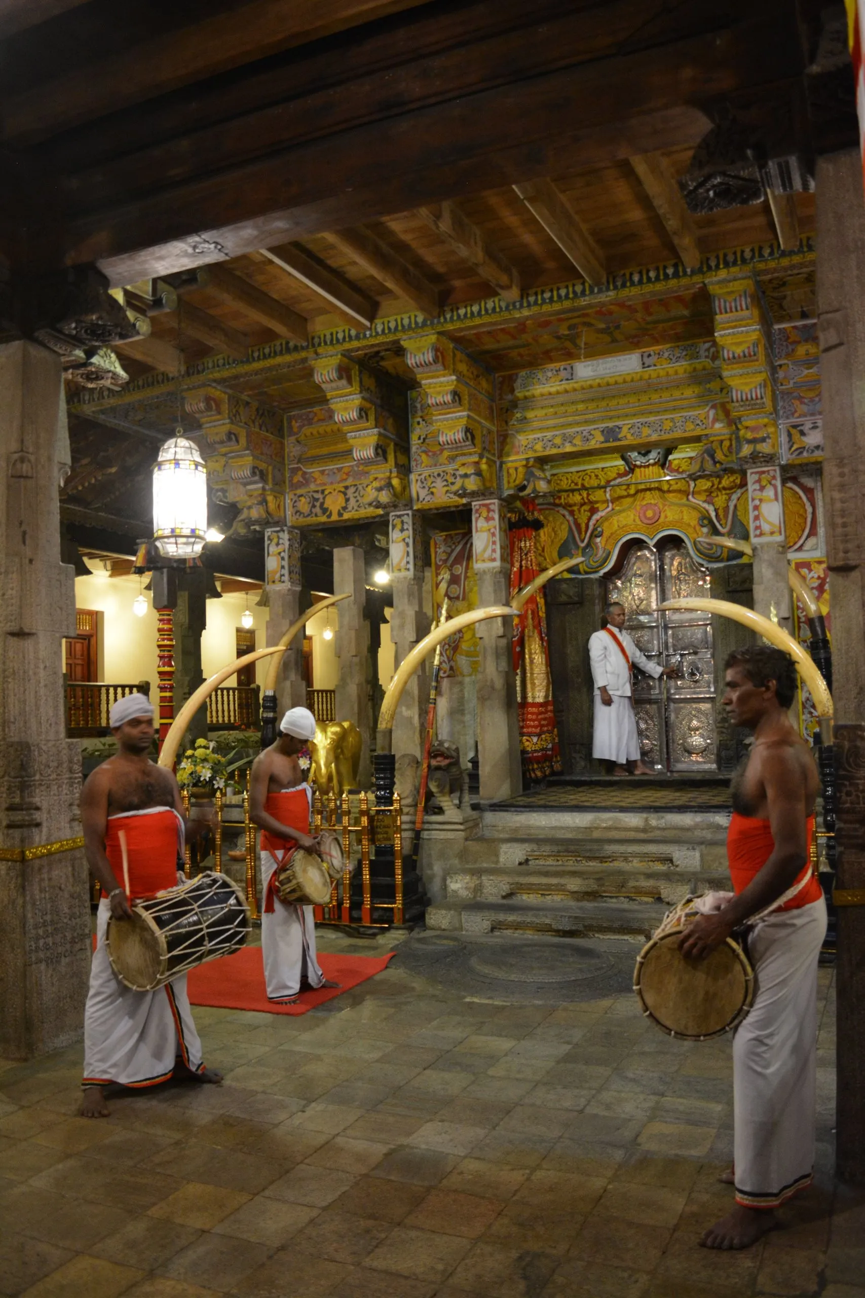 Temple drummers in white playing under a painted ceiling