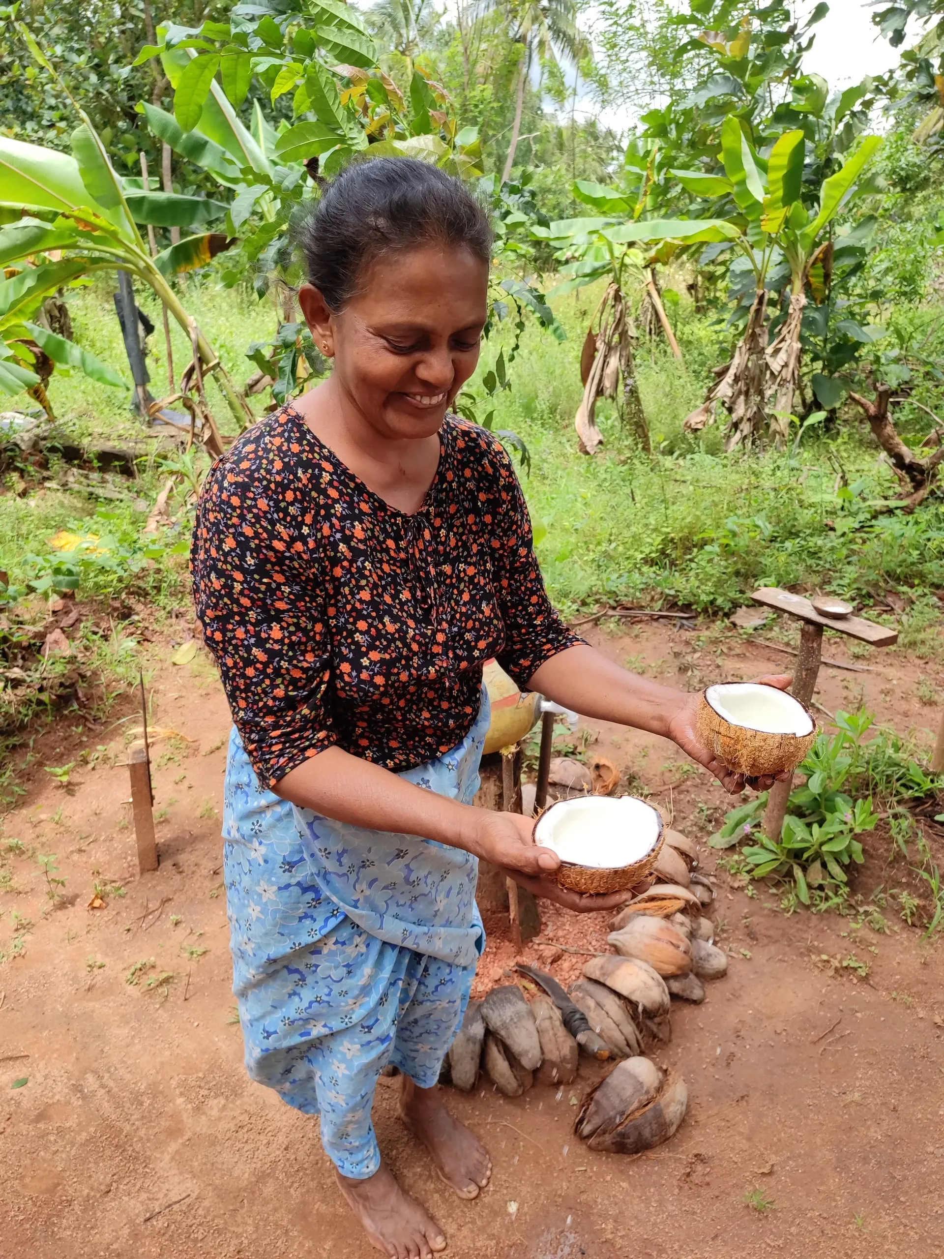A woman holding two halves of a freshly opened coconut